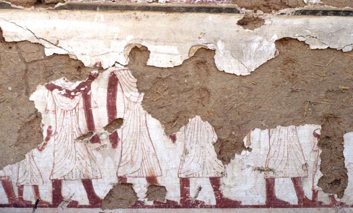 Damaged fresco showing 7 figures in long white robes and shaved heads walking from the left to the right.
