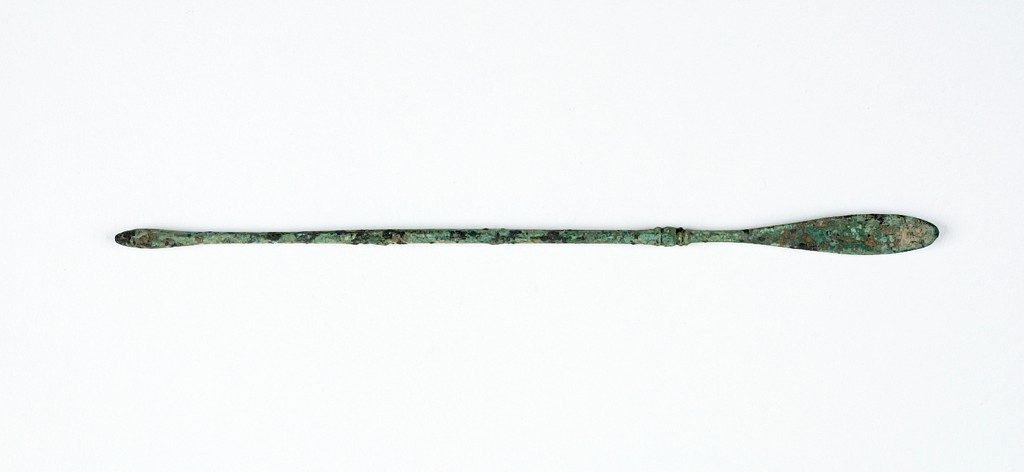 Image of a long thing copper spoon, slightly corroded.