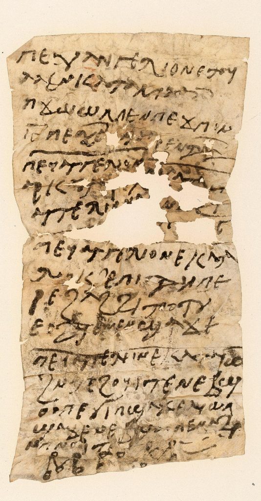 A tall, slim sheet of parchment, showing several horizontal and vertical folds, and considerable damage in the centre. It is covered with Coptic text, while at the bottom a few signs are visible, resembling Greek or Coptic letters, with circles drawn at each corner.