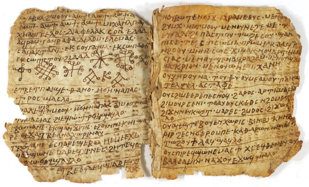 Image of a parchment codex, open to show two pages written with Coptic text and some magical symbols. There is some damage to the outer edges of the pages.