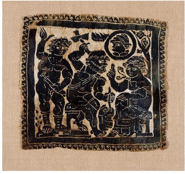 An embroidered panel showing a seated woman sitting in front of a seated man with a hammer. A second naked man holding a sword stands behind the first, and there is a shield with a man's face on it above the seated figures.